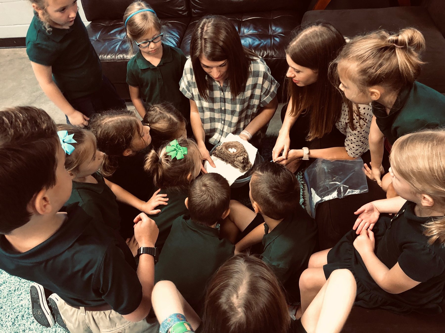 Evergreen students gather around a teacher to explore a bird’s nest